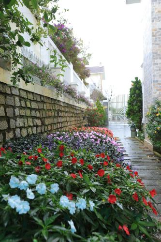 un jardin de fleurs à côté d'un mur de briques dans l'établissement The Hill Villa - Đà Lạt, à Xuan An