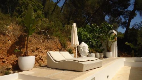 a white chair and an umbrella and potted plants at Villa Romeo in Sant Jordi
