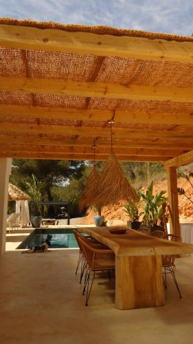 a wooden table with chairs under a wooden roof at Villa Romeo in Sant Jordi