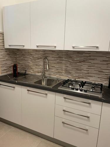 a white kitchen with a sink and a stove at Casa Moly in Monopoli
