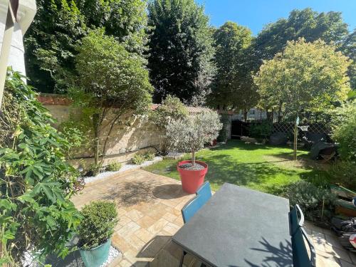d'une terrasse avec une table et des chaises dans le jardin. dans l'établissement Large duplex, quiet garden, in private mansion, à Neuilly-sur-Seine