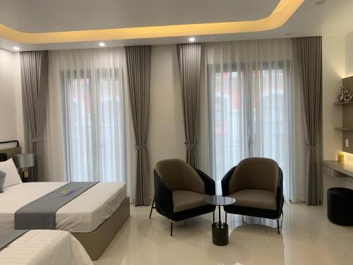 a hotel room with a bed and two chairs at Sunny Hotel in Ðố Sơn