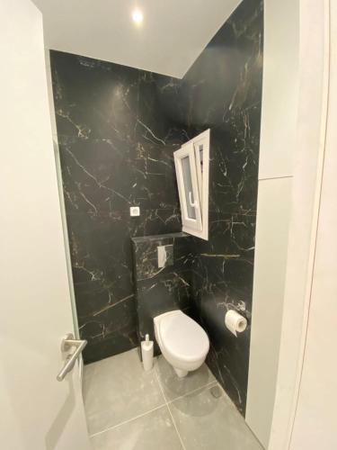 a bathroom with a toilet and a black wall at Elegant and spacious penthouse in Mesochórion