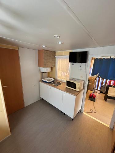 une petite cuisine avec un four micro-ondes sur un comptoir dans l'établissement mobil home numéro 76, à Meschers-sur-Gironde