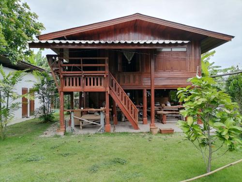 a large wooden building with a staircase in a yard at Lanna house Sankampaeng บ้านหอเสื้อสันกำแพง in Ban Doi Yao