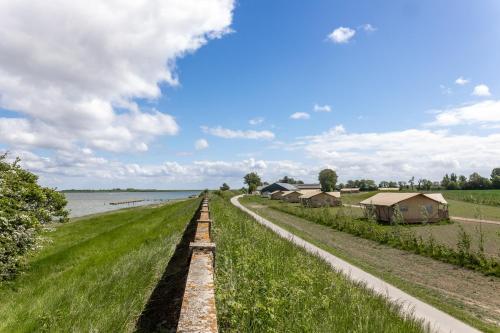 a dirt road next to a body of water at Glamping De Zuidvliet Nr 12 in Wolphaartsdijk