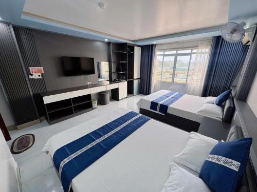 a large room with two beds and a tv at New Way Hotel in Cat Ba