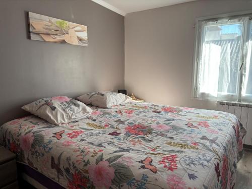 une chambre avec un lit avec une couette fleurie dans l'établissement Maisonnette au pied du marché et 300 m de la plage, à Saint-Georges-de-Didonne