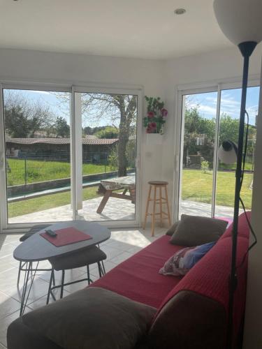 a bedroom with a bed and a table and sliding glass doors at Villa HESTIA in Le Teich