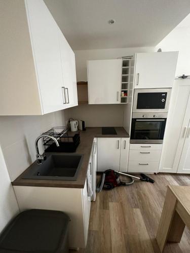 une cuisine avec des armoires blanches et un évier dans l'établissement Studio - port de Nice - balcon, à Nice