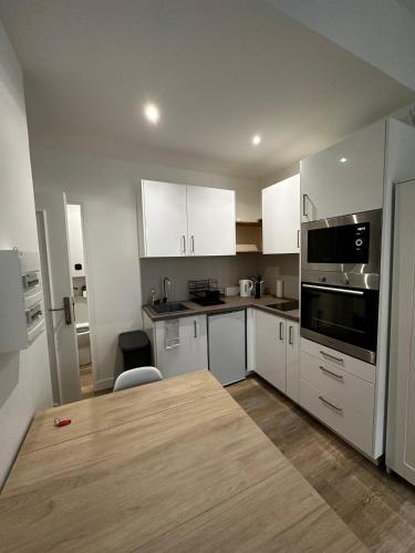 une cuisine avec des armoires blanches et une table en bois dans l'établissement Studio - port de Nice - balcon, à Nice