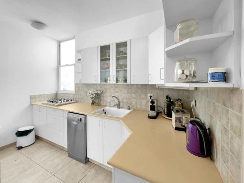 a white kitchen with white cabinets and a sink at Elegant Beachside Apartment in Herzliyya B