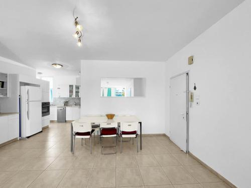 a white kitchen with a table and chairs at Elegant Beachside Apartment in Herzliyya B