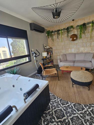 a living room with a bath tub and a couch at APTER-Boutique Apartment אפטר - דירת בוטיק בכנרת in Tiberias