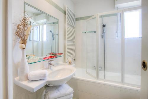 a white bathroom with a sink and a shower at Hotel Ca' Bianca in Riccione