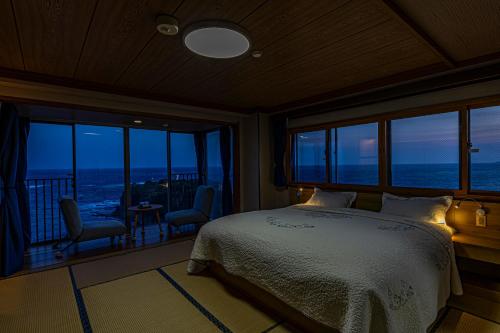 a bedroom with a bed and a view of the ocean at Ocean View Hiromi SPA Hotel温泉と絶景の宿 in Shimoda