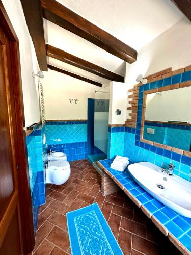a blue tiled bathroom with a sink and a toilet at Villa Mameli b&b in Rena Majore