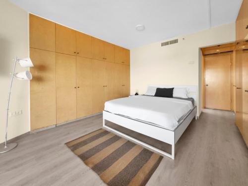 a bedroom with a large white bed and wooden cabinets at The Sharon Secret Pearl in Herzliyya B