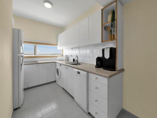 a white kitchen with a sink and a refrigerator at The Sharon Secret Pearl in Herzliyya B