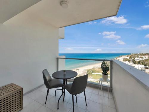 a balcony with a table and chairs and a view of the beach at The Sharon Secret Pearl in Herzliyya B