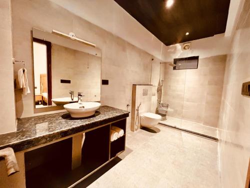 a bathroom with a sink and a toilet and a mirror at Sitara Hotel & Resorts, Haridwar in Haridwār