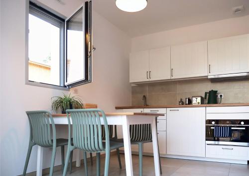 une cuisine avec des armoires blanches et une table et des chaises dans l'établissement New Studio 30m2 near beach with garden and terrace, à Seignosse