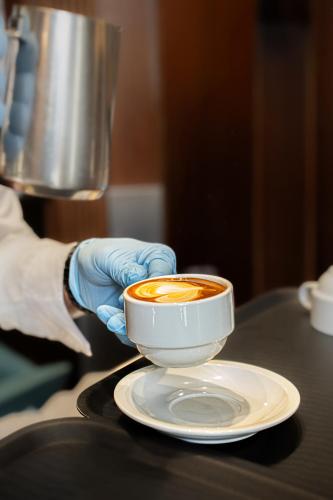 a person in blue gloves holding a cup of coffee at Hotel Miami in Rome