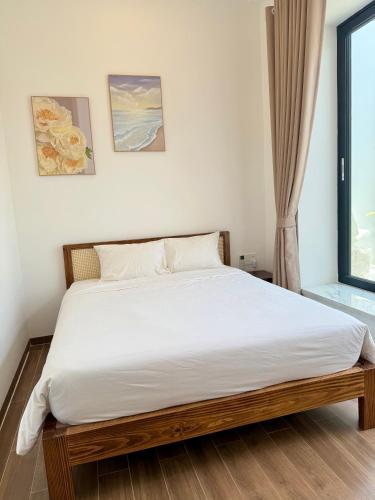 a bedroom with a bed with white sheets and a window at Hi Homestay - Near Kitesurfing My Hoa in Phan Rang