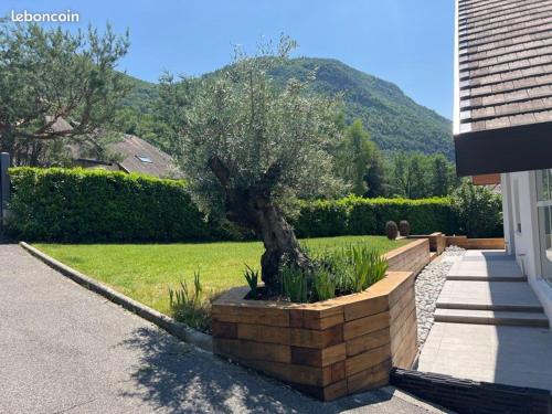 un arbre dans un planteur de pierre à côté d'une maison dans l'établissement Villa avec piscine à 5 minutes du lac, à Annecy