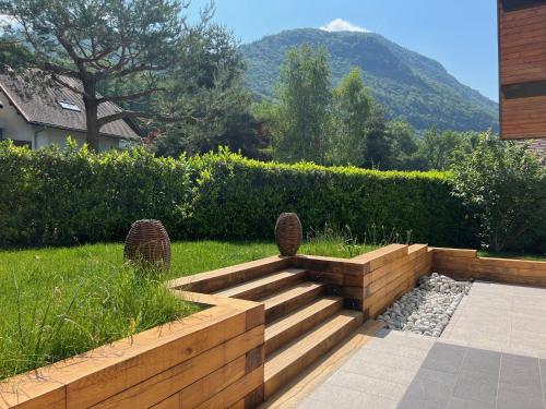 un jardin avec un escalier en bois avec une montagne en arrière-plan dans l'établissement Villa avec piscine à 5 minutes du lac, à Annecy