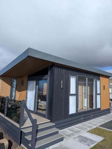 a small black house with a porch and stairs at Lyons Sunnysands Caravan Park in Barmouth