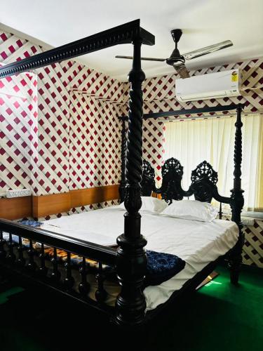 a bedroom with a black canopy bed with white sheets at Panama & Panama Hotel and Restaurant in New Town