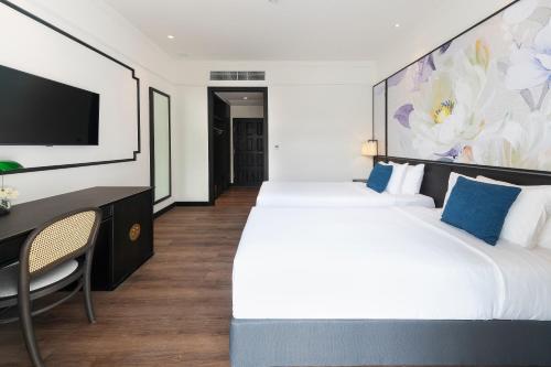 a bedroom with two beds and a desk and a tv at Indochina Hotel in Aranyaprathet