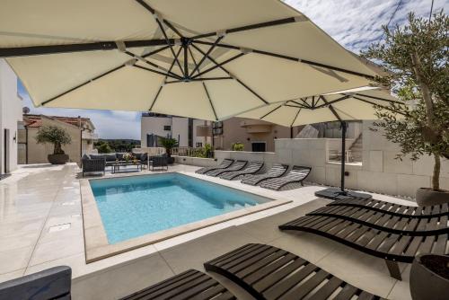a swimming pool with chairs and umbrellas at Villa Lavea in Trogir