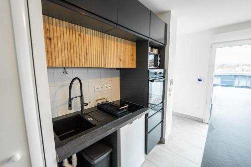 - une cuisine avec des placards noirs et un évier dans l'établissement Peaceful stay near Pessac forest, à Pessac