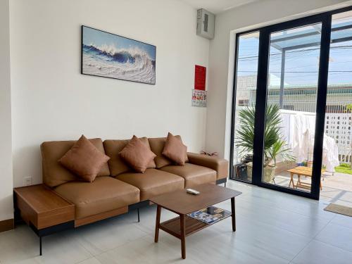 a living room with a brown couch and a table at Hi Homestay - Near Kitesurfing My Hoa in Phan Rang
