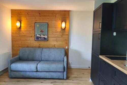 un salon avec un canapé bleu et une télévision dans l'établissement Apartment with pool at the foot of the slopes, à Flumet