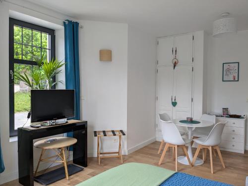 un salon avec une télévision, une table et des chaises dans l'établissement Les Jolis Nids - Appartement Perroquet, à La Roche-Posay