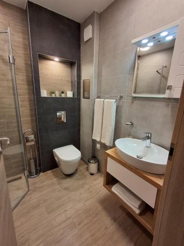 Un baño con lavabo, inodoro y ducha. en Azur Oasis, en Varna