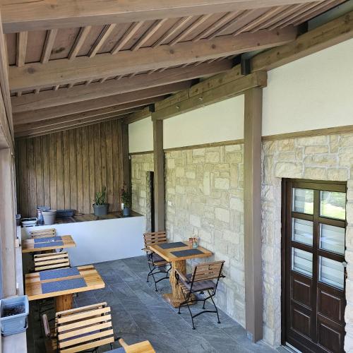a patio with tables and chairs and a stone wall at Plitvice Streaming in Prijeboj
