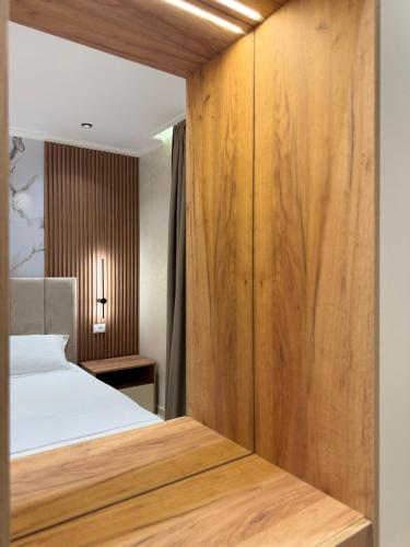 a bedroom with a bed and a wooden wall at Kamberi Hotel & Apartments in Velipojë