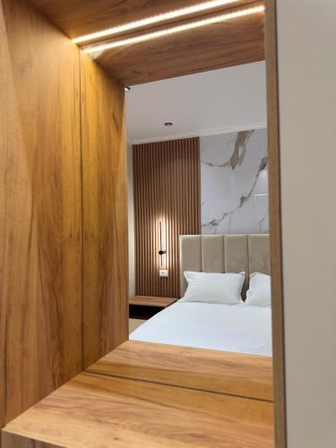 a bedroom with a white bed and wooden walls at Kamberi Hotel & Apartments in Velipojë