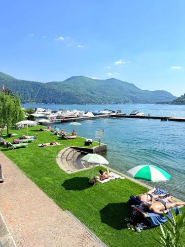 a group of people laying on the grass next to a lake at Gritti Palace Morcote - Waterfront studio with panoramic lake views - Fiordaliso in Morcote