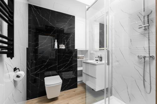 a bathroom with a toilet and a glass shower at Apartamenty Solaris in Darłówko