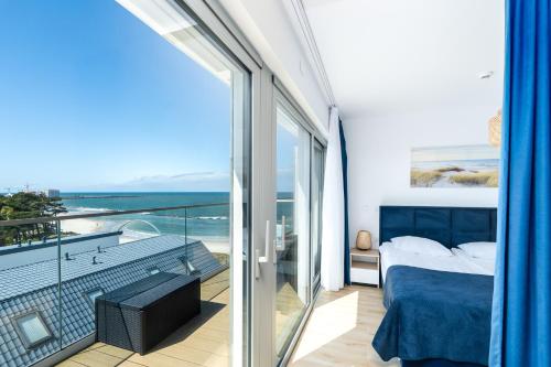 a bedroom with a bed and a balcony with the ocean at Apartamenty Solaris in Darłówko