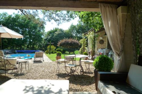 un patio avec des chaises, une table et un parasol dans l'établissement Beautiful Provencal villa with pool and jacuzzi, à Lacoste