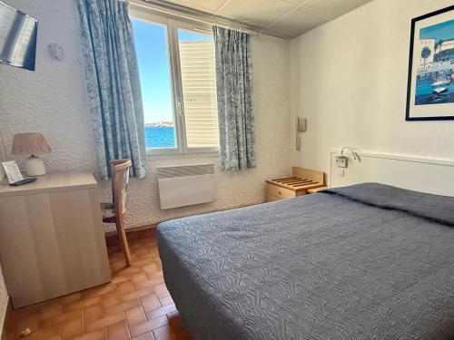 a bedroom with a bed and a desk and a window at Hotel L'ondine in Algajola