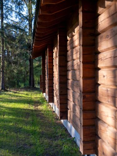 a side of a wooden building with grass on the side at River Mind Villa with SPA in Zalioji