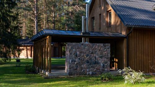 a wooden cabin with a stone wall and a roof at River Mind Villa with SPA in Zalioji