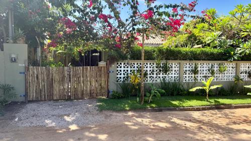 a fence in a yard with pink flowers at Bangalô de Charme na Praia do Patacho - Rota Ecológica dos Milagres in Pôrto de Pedras